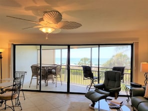Une chambre dotée d’un ventilateur de plafond, d’un balcon avec une table et des chaises, et offrant une vue sur l’océan.