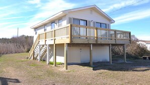 A two-story house with a wooden deck and a staircase leading to the upper floor. - 385 Cute 3 Bedroom Cottage in South Nags Head (Nags Head)