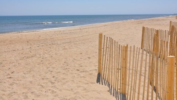 A sandy beach with a wooden fence and a clear sky. - 385 Cute 3 Bedroom Cottage in South Nags Head (Nags Head)
