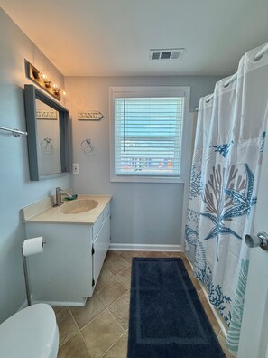 A bathroom with a sink, mirror, toilet, and shower curtain.
