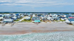A coastal residential area with houses on stilts over the beach, connected by walkways. - Riki Tiki | Oceanfront Home in Surf City (Surf City)