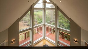 A room with large windows, a wooden deck, and a ceiling fan.