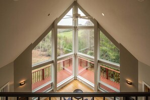 Una habitación con amplios ventanales, una terraza de madera y un ventilador de techo.
