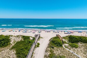 A beach with a wooden boardwalk, sandy beach, and ocean view.