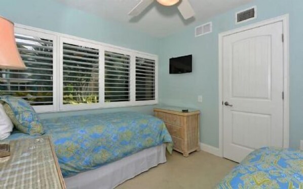 A bedroom with two beds, a window with blinds, a television on the wall, and a door. - Firethorn 110- Absolutely gorgeous, beachfront 2BR/2BA condo (Siesta Key)