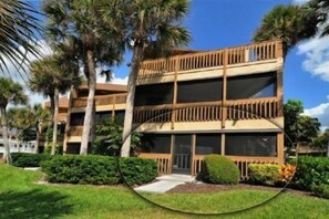 A multi-story hotel with balconies, surrounded by palm trees and greenery.