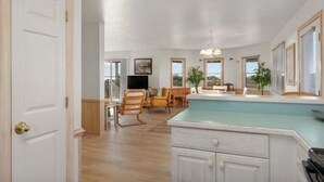 A spacious living area with a dining table, chairs, a TV, and a kitchen counter.