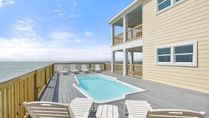 A pool area with lounge chairs and a view of the ocean. - Shamrock Shores - Gulf-front 6 Bedroom Beach House, 2 kitchens, Pet-Friendly (Dauphin Island)