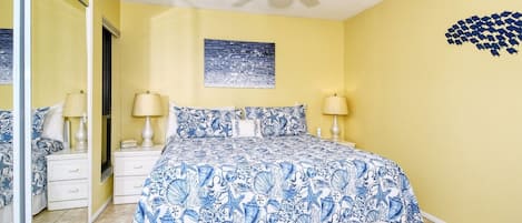 Ein Schlafzimmer mit einem Bett, zwei Nachttischen, einem Deckenventilator und einer Wand mit einem gerahmten Bild.