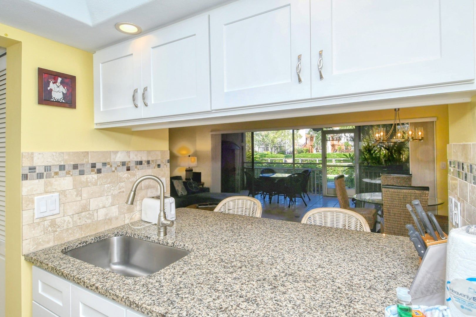 A kitchen with granite countertops, white cabinets, and a built-in sink.