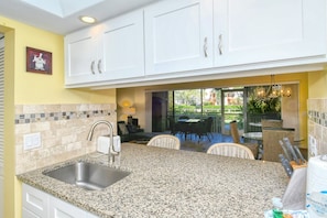 A kitchen with granite countertops, white cabinets, and a built-in sink.