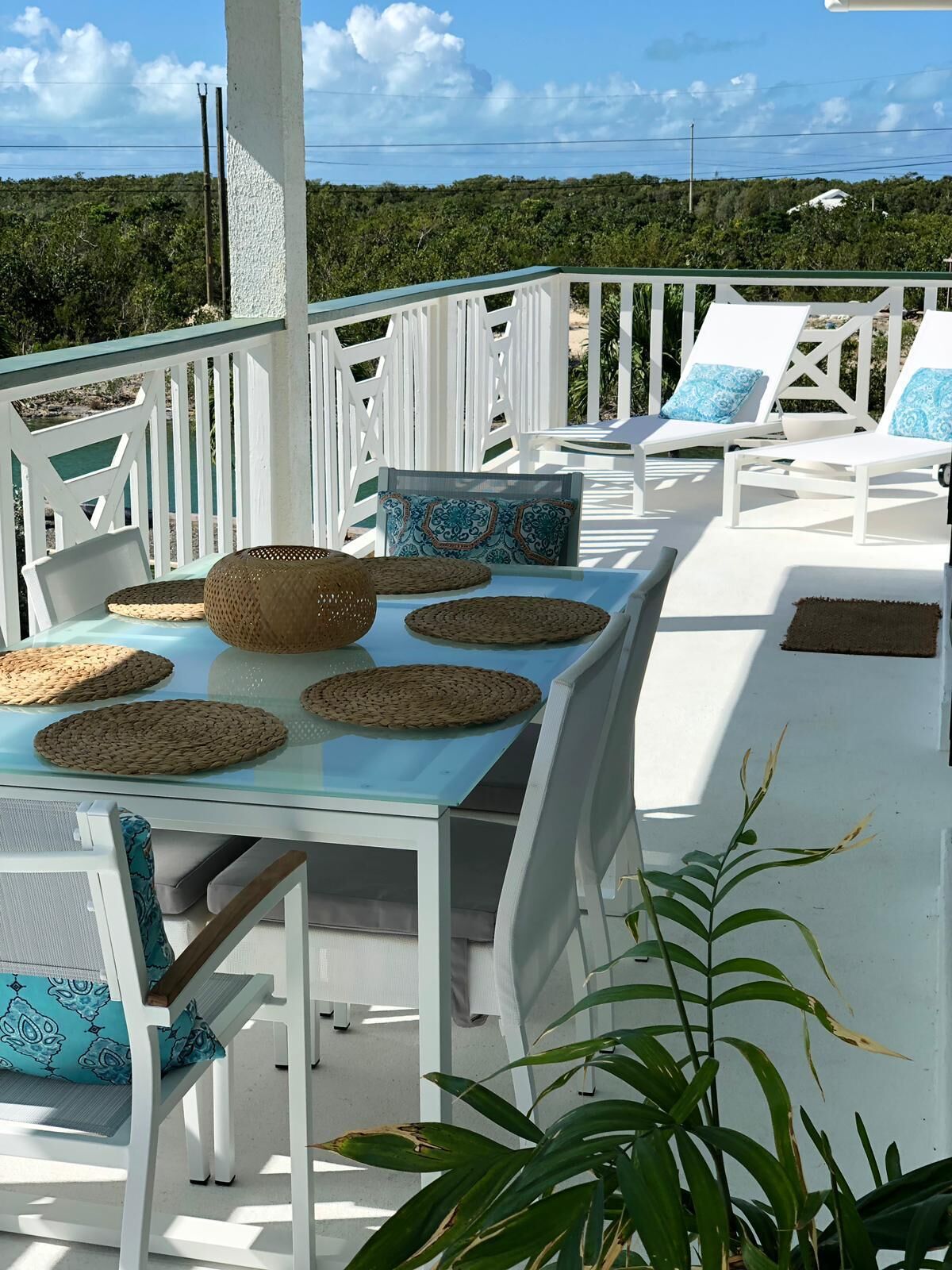 A sunlit outdoor seating area with white furniture and woven placemats.