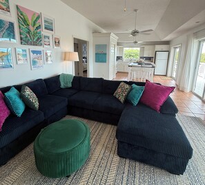 A living room with a sectional sofa, ottomans, and a patterned rug.