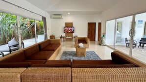 Een moderne woonkamer met een grote bruine bank, een rieten salontafel en een televisie.