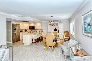 A modern kitchen with a central island, bar stools, and a dining area with wicker chairs.
