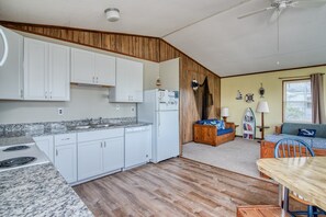 Cozy home with a kitchen and living area, featuring a stove, wooden sofa, and bookshelf.