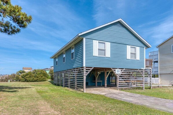 A two-story house with a blue exterior, a front porch, and a wooden deck.