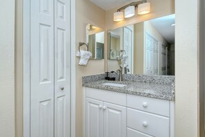 A bathroom with a granite countertop, a sink, a mirror, and white cabinetry. - Doveplum 621- 2 Story, 2 Bedroom Condo with Private Beach with lounge chairs & umbrella provided,... (Siesta Key)