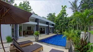 Uma casa moderna com piscina, área de estar externa e vegetação exuberante.