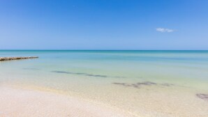 A clear beach with calm waters and a wooden pier extending into the sea. - Private Oasis On The Beach (Progreso)