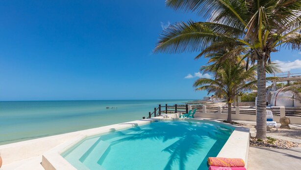 A poolside view with a clear blue sky, a calm sea, and a wooden fence. - Private Oasis On The Beach (Progreso)
