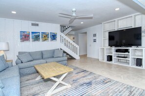 A living room with a sofa, coffee table, TV stand, and artwork on the wall.