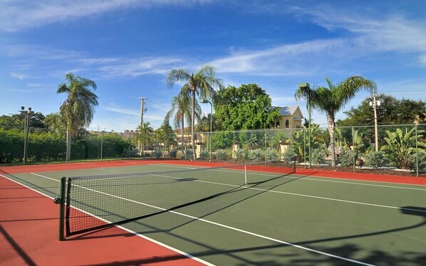 An outdoor tennis court with a net, surrounded by palm trees and a fence. - Chinaberry 951-Unwind in a beautifully remodeled 2 bedroom, 2 bathroom unit with great amenities (Siesta Key)
