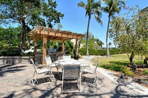 Eine Terrasse im Freien mit einer Pergola, einem runden Tisch und Metallstühlen.