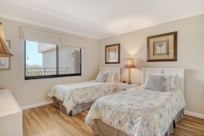 Ein Schlafzimmer mit zwei Betten, einem Fenster und einem Balkon.