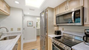 A modern kitchen with a stainless steel refrigerator, a microwave, a toaster, and an oven. - Firethorn 821-  2-bedroom, 2-bathroom second floor condo overlooking canal w/private beach access (Siesta Key)