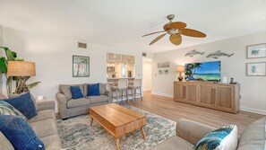 A living room with a sofa, coffee table, and a ceiling fan.