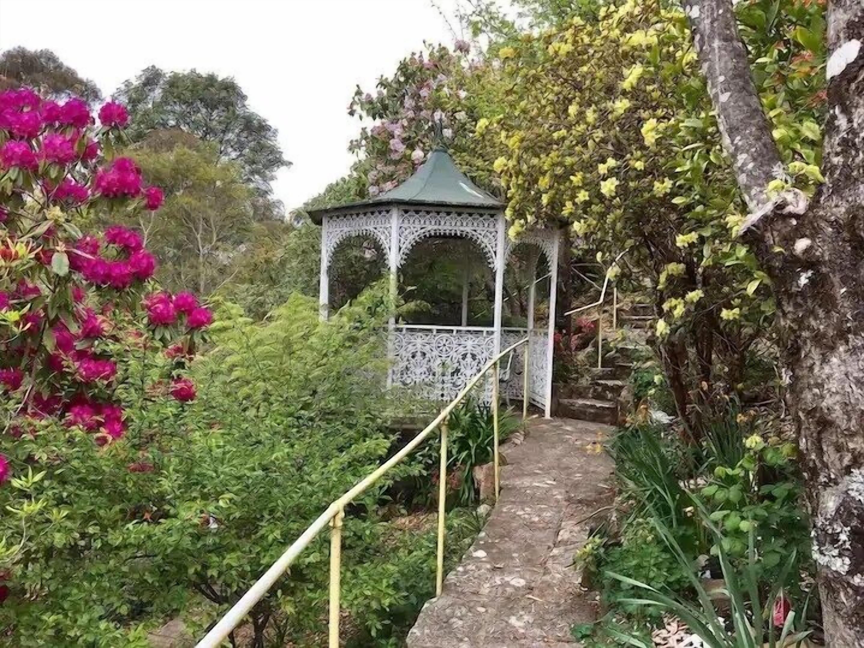 A garden pathway leading to a gazebo with intricate white lattice work.