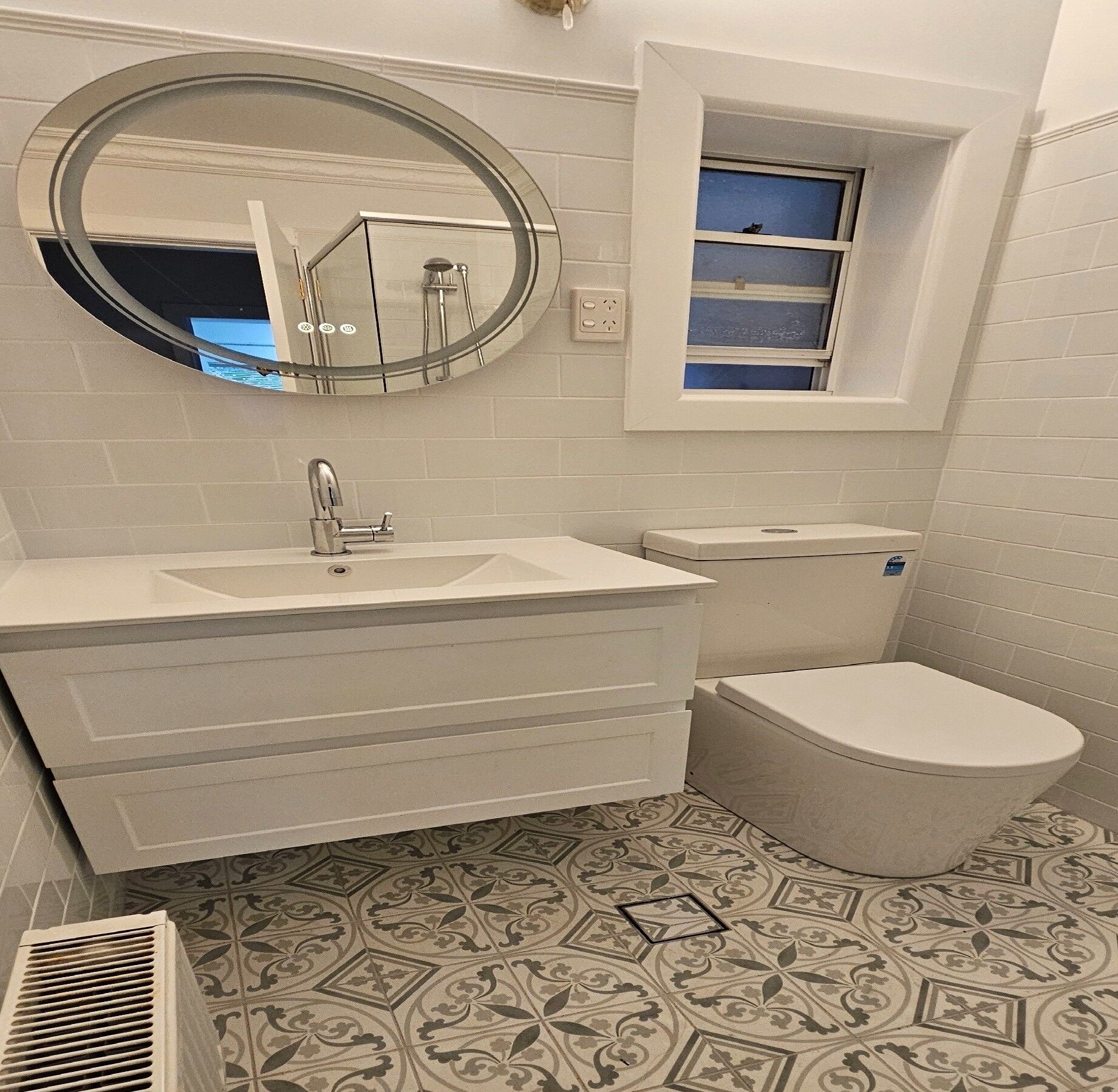 A bathroom with a white sink, a toilet, a window, and a mirror.