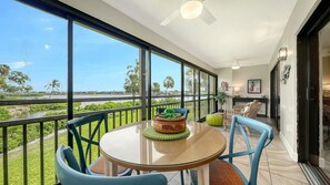 A balcony with a table and chairs, a view of a river, and a door leading to an interior space. - Chinaberry 922- 2-bedroom / 2-bathroom unit feat breath taking views of Sarasota's Intracoastal Bay. (Siesta Key)