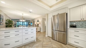 A modern kitchen with white cabinetry, a stainless steel refrigerator, and a tiled floor.