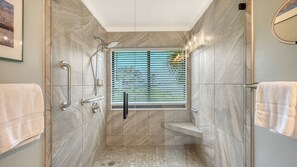 A modern shower with a glass door, a handrail, and a window with blinds. - Chinaberry 922- 2-bedroom / 2-bathroom unit feat breath taking views of Sarasota's Intracoastal Bay. (Siesta Key)