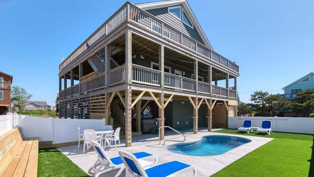 Un bâtiment à deux étages doté d’un balcon, d’une piscine et d’un espace extérieur aménagé pour s’asseoir.