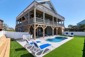 A two-story building with a balcony, a swimming pool, and outdoor seating.