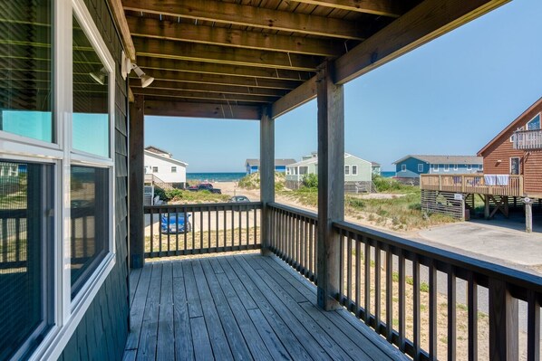 A wooden deck with a view of the beach and beach houses.