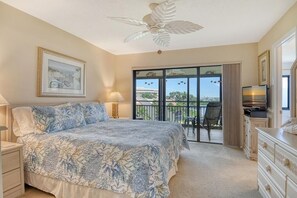 Ein Schlafzimmer mit Bett, Deckenventilator, Fernseher und einem Balkon mit Blick.