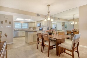 A spacious kitchen with a central island, wooden dining table, and chairs. - Chinaberry 952-Gorgeous intra coastal waterway view from this fifth floor two bedroom/two bath unit. (Siesta Key)