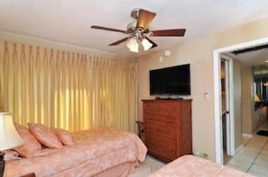 A hotel room with a bed, a television, a ceiling fan, and a wardrobe.