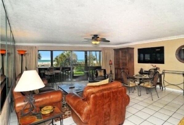 A hotel room with a seating area, a television, and a view of the ocean.