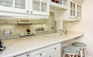 A kitchen with white cabinetry, a countertop, and two stools.