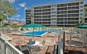 A hotel with a swimming pool, outdoor seating, and a fenced patio area.