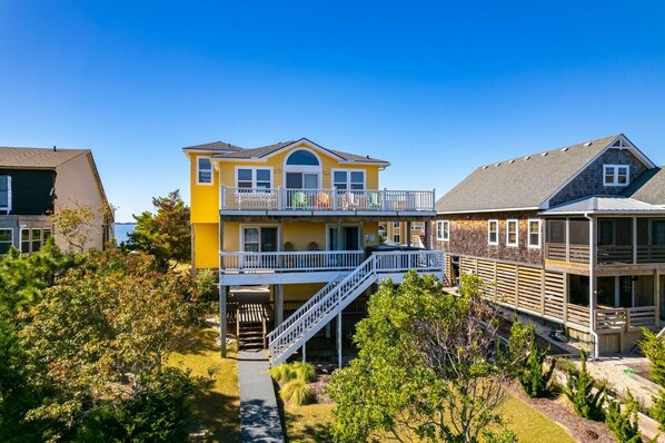 A two-story house with a balcony, a staircase, and a view of the water. - 433 Water-Front w/ Multi-Level Decking & Hot Tub (Nags Head)