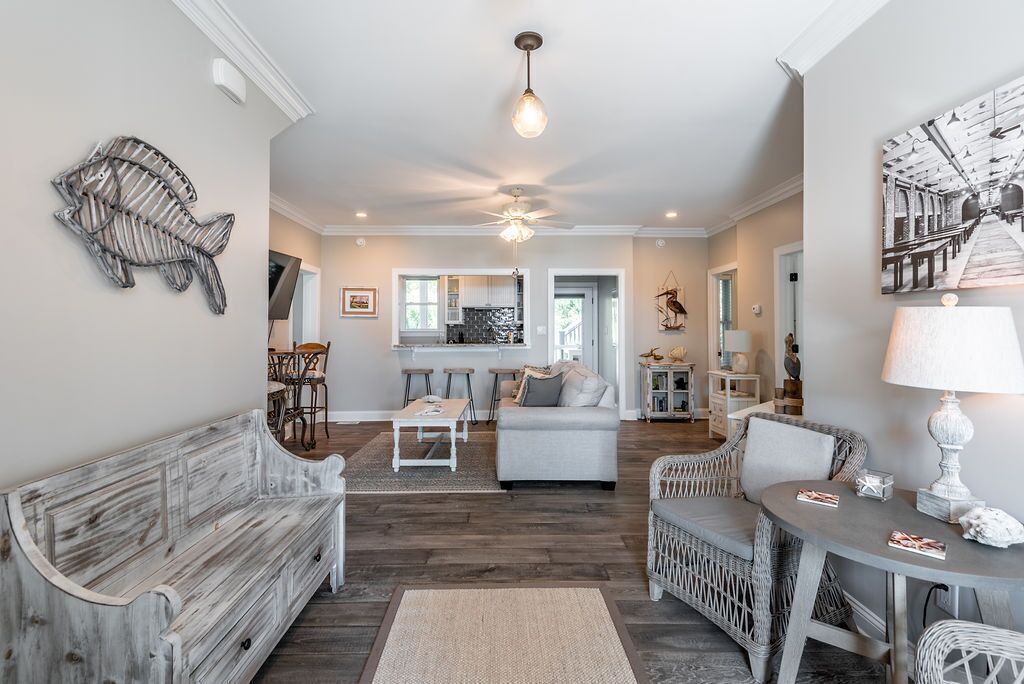 A spacious living room with a wooden bench, a round table, and a sofa. There is a ceiling fan and a wall-mounted light fixture.