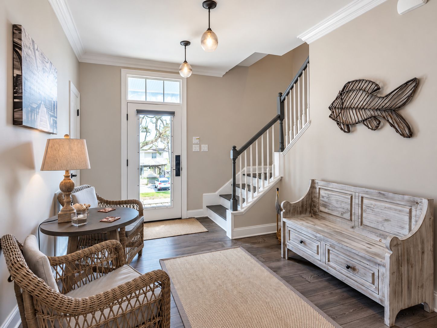 A living room with a sofa, a dining table with chairs, a lamp, a staircase, and a wall-mounted decorative piece.