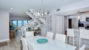 Une cuisine moderne avec des meubles blancs, des appareils en acier inoxydable et un grand îlot central.