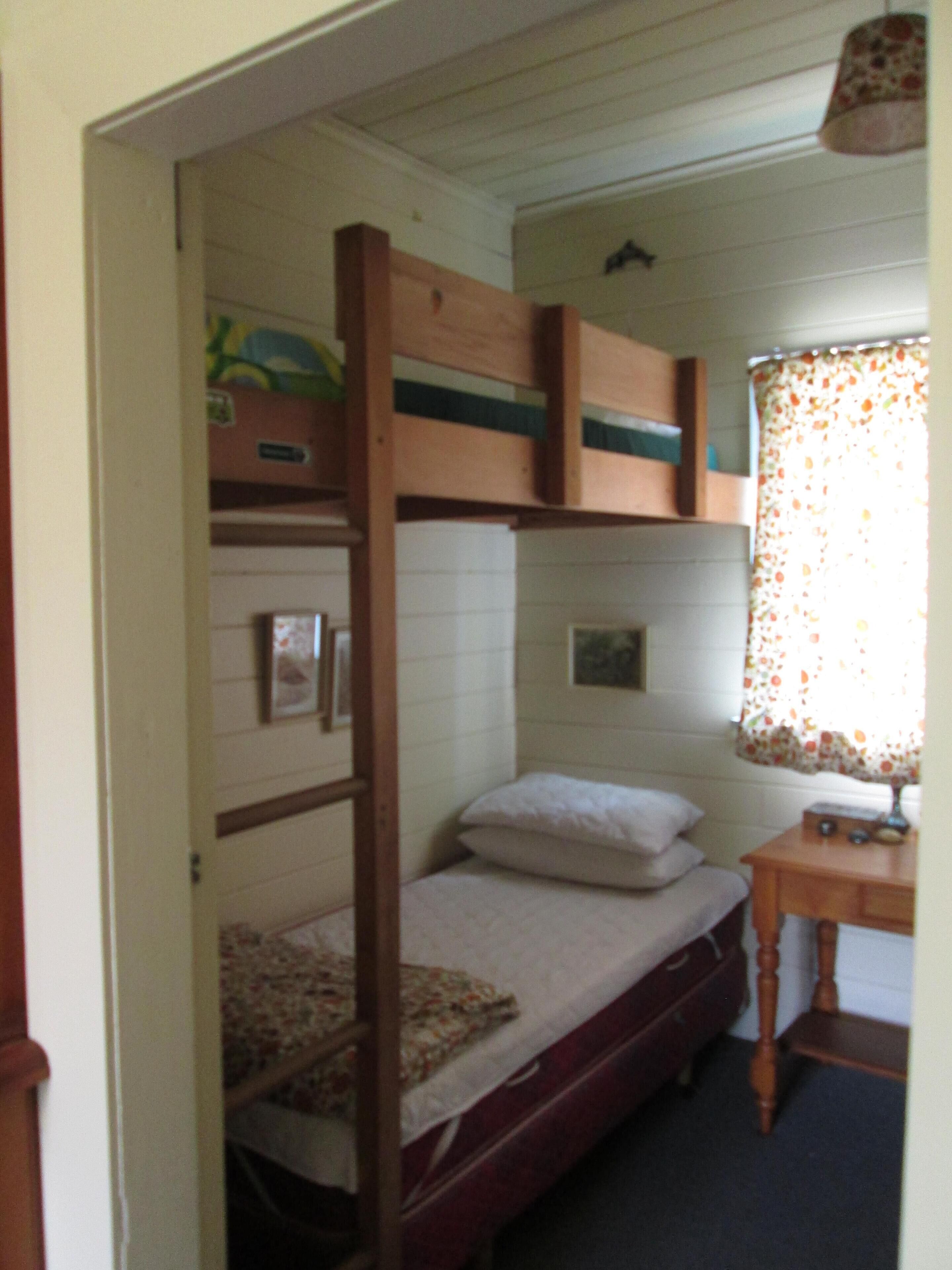 Habitació amb lliteres, una taula petita i una finestra amb cortines florals.